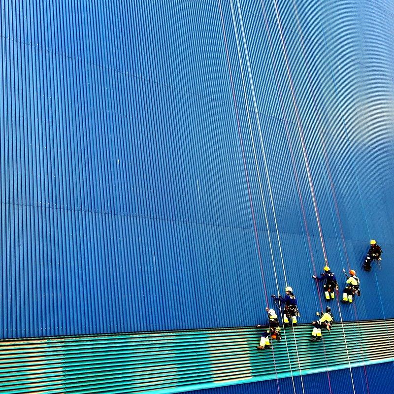 Team von Industriekletterern an einer großen Hallenfassade