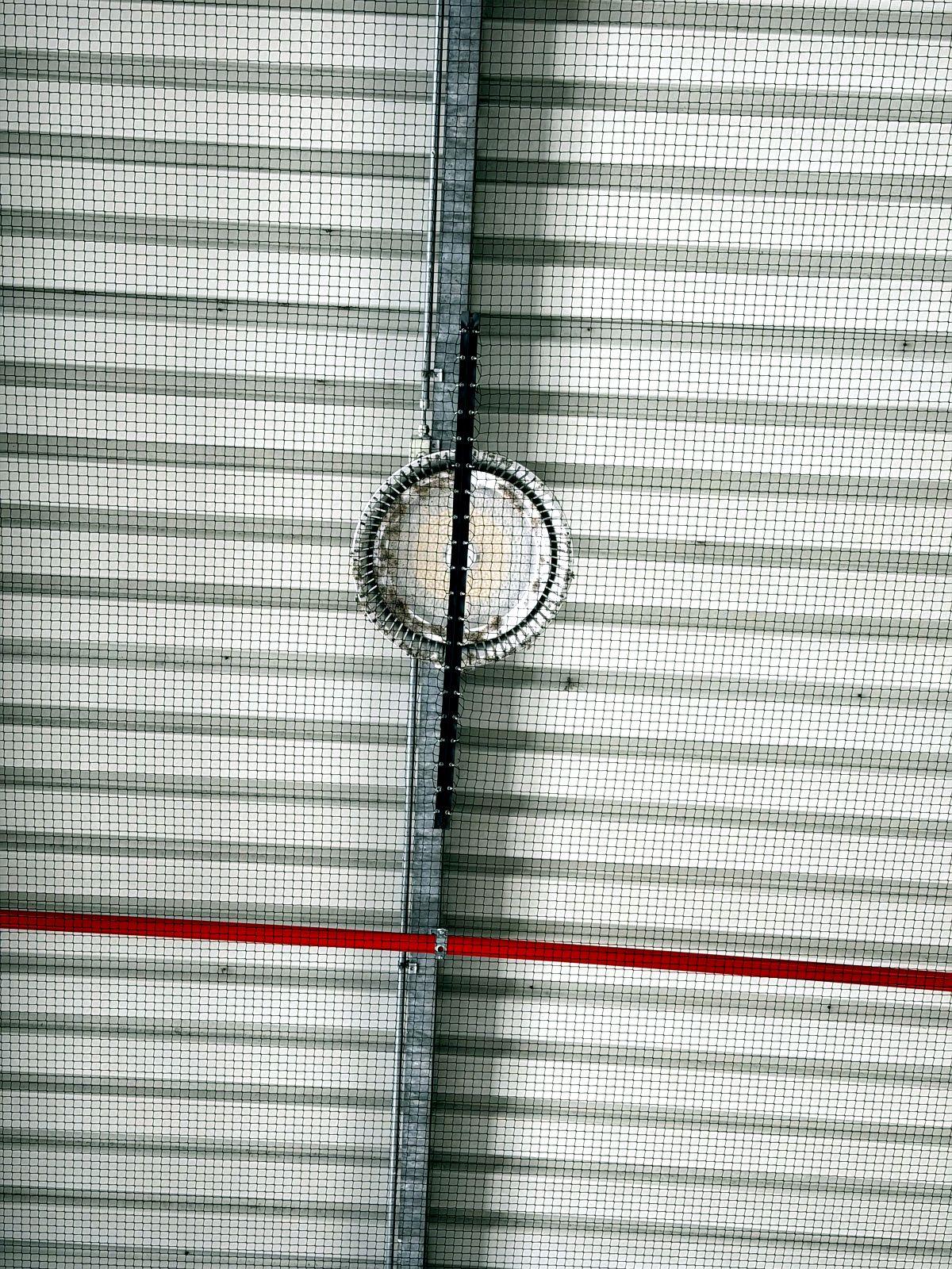 Zipper built into the pigeon netting as a maintenance hatch near a light fixture