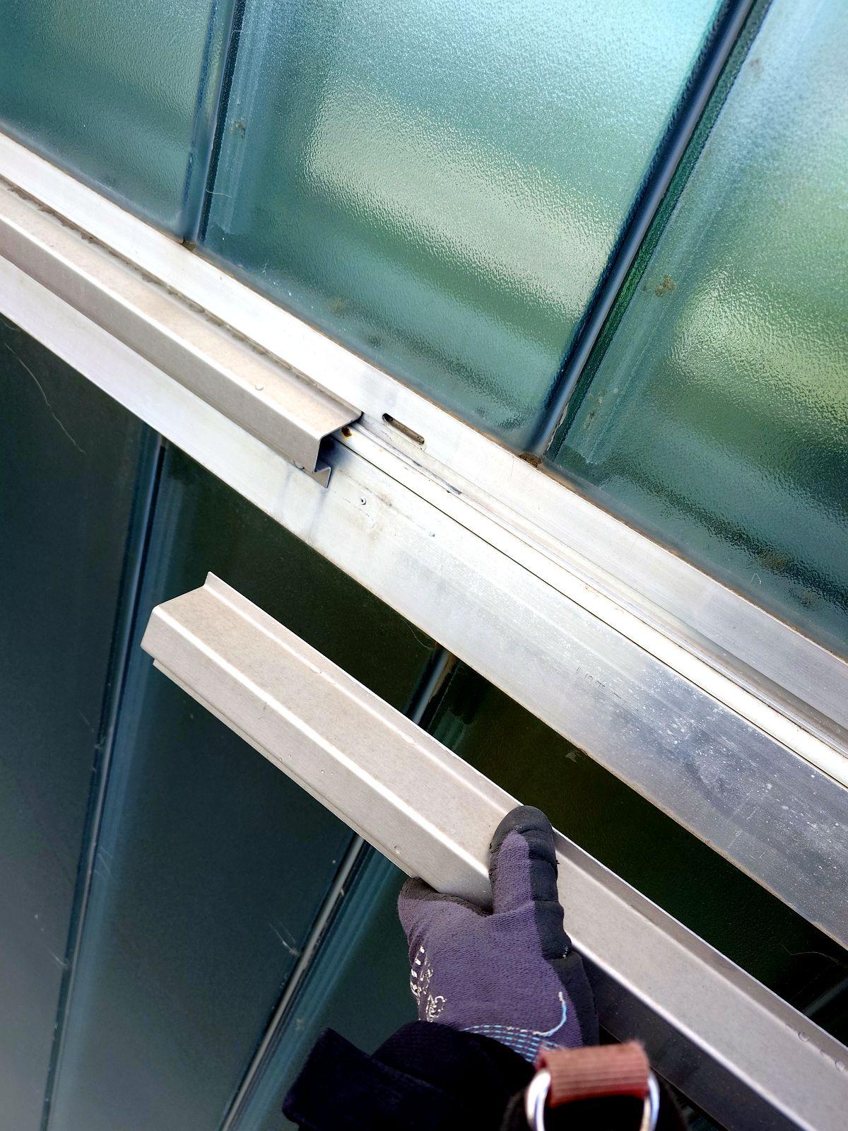 Lose Fassadenleiste nach Sturmschaden wird zur Reparatur gehalten