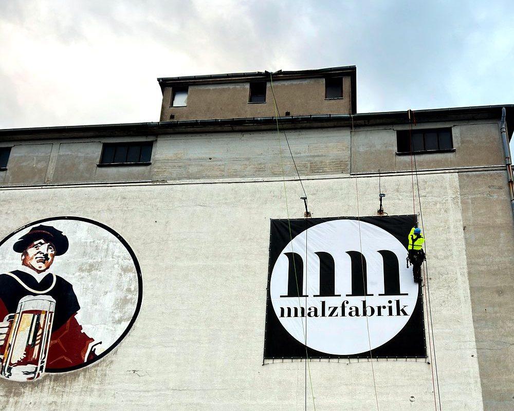 Montage eines großformatigen Werbebanners an einer Fassade per Seilzugangstechnik
